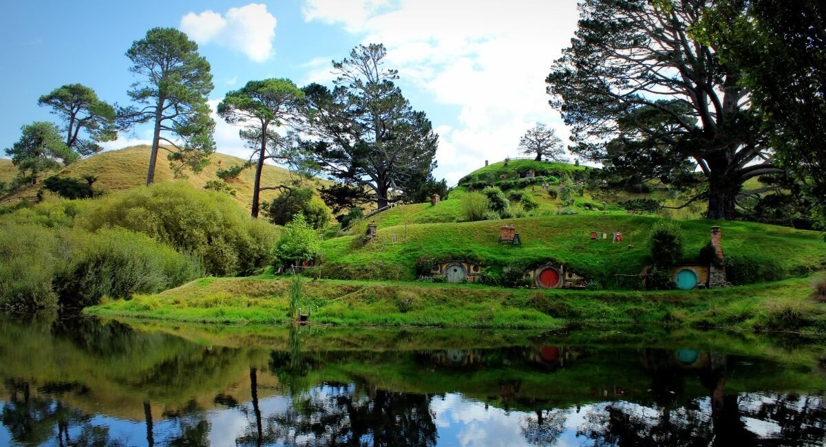 Tocas de hobbit refletidas no lago de Hobbiton, na Nova Zelândia