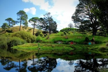 Tocas de hobbit refletidas no lago de Hobbiton, na Nova Zelândia