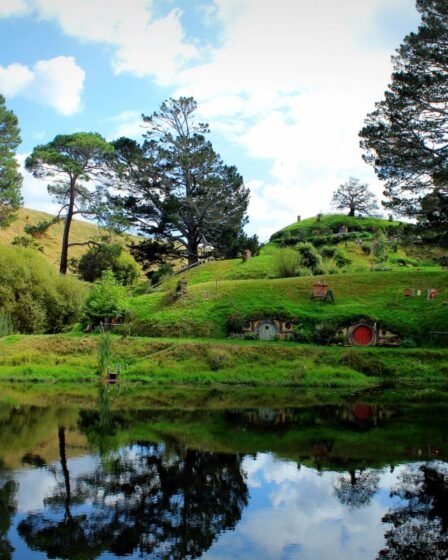 Tocas de hobbit refletidas no lago de Hobbiton, na Nova Zelândia